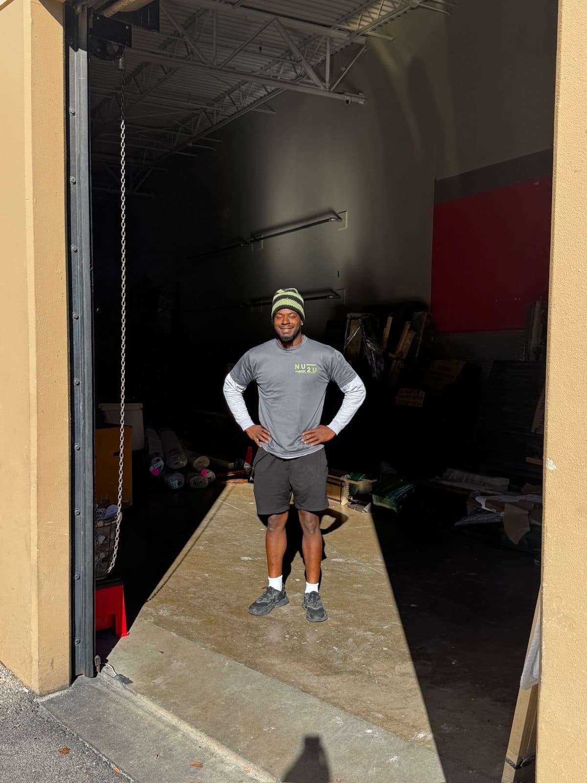 A smiling Nu2U mover in a branded shirt standing at a warehouse loading door