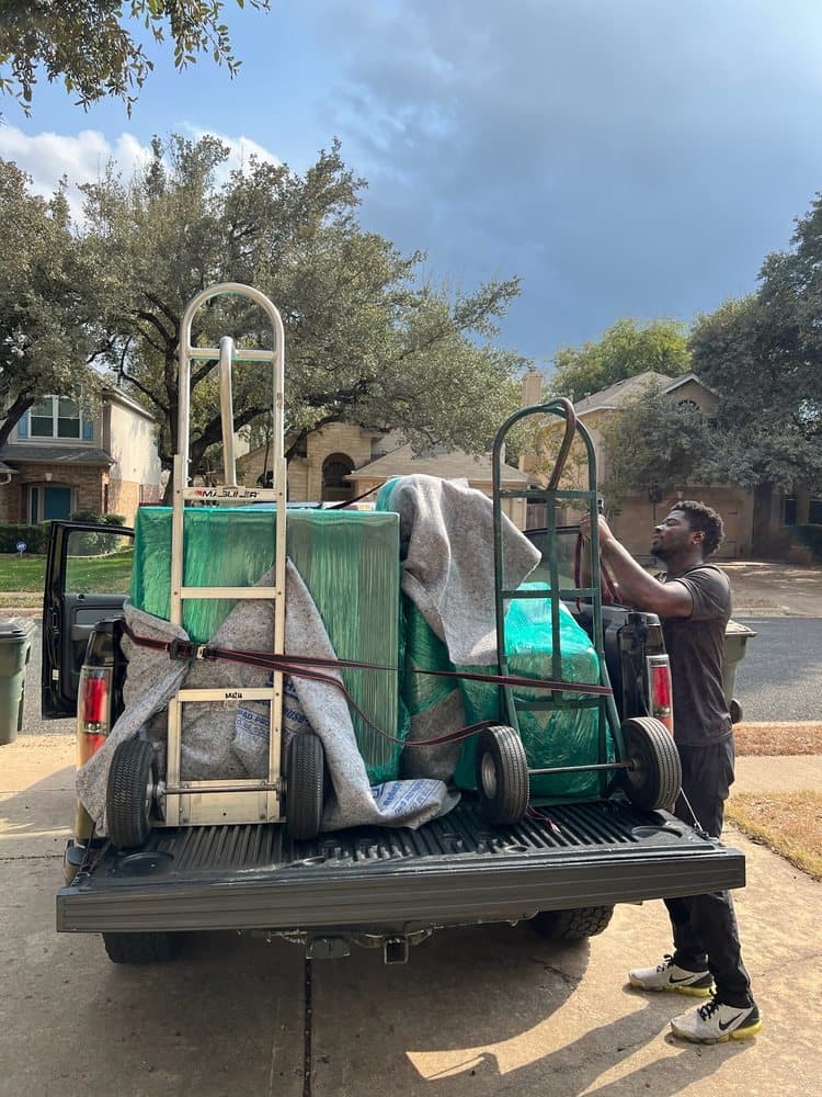 A Nu2U mover strapping hand trucks and wrapped furniture into a pickup bed