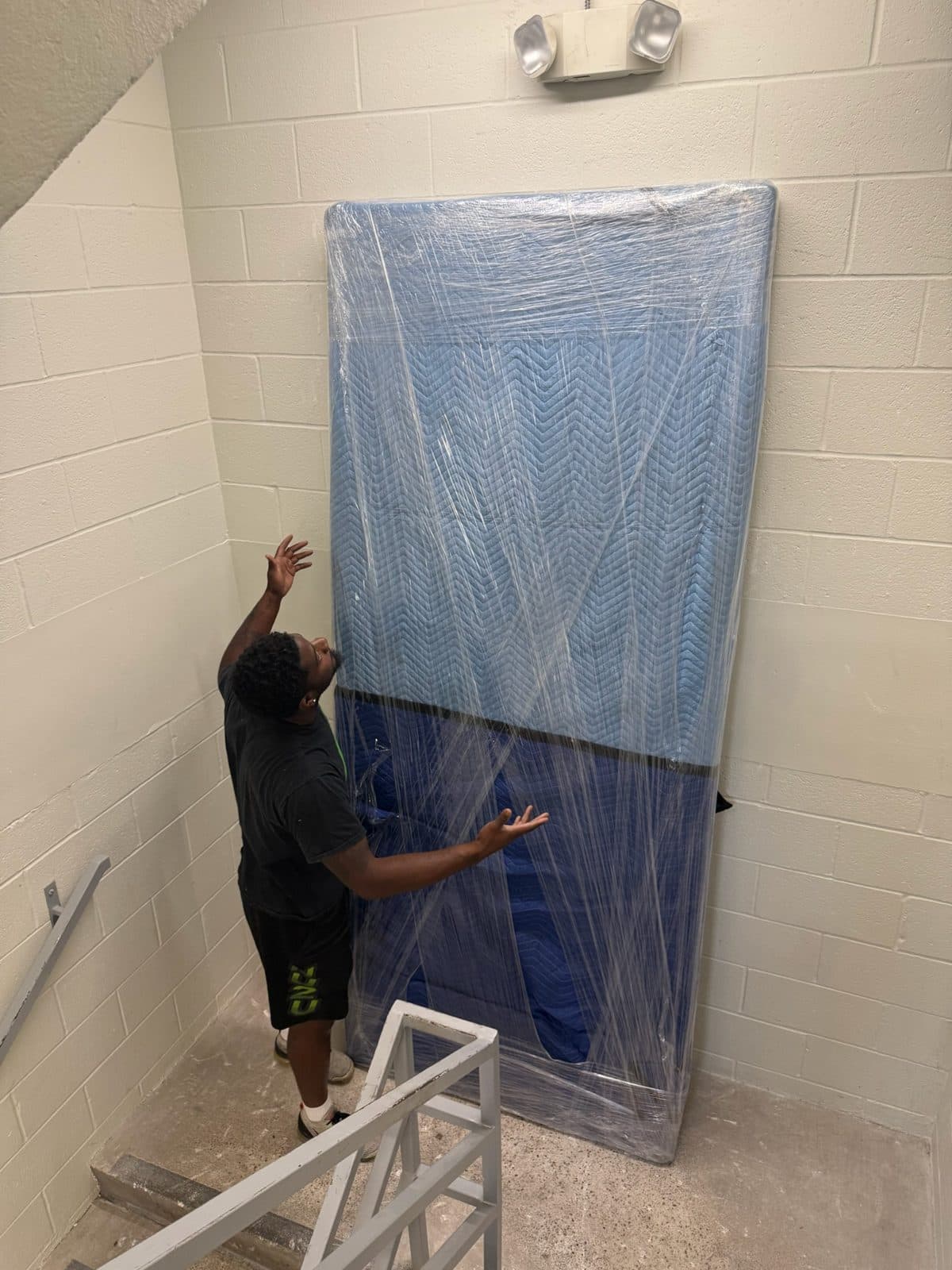 A Nu2U mover with a large blanket-wrapped tabletop in an apartment stairwell